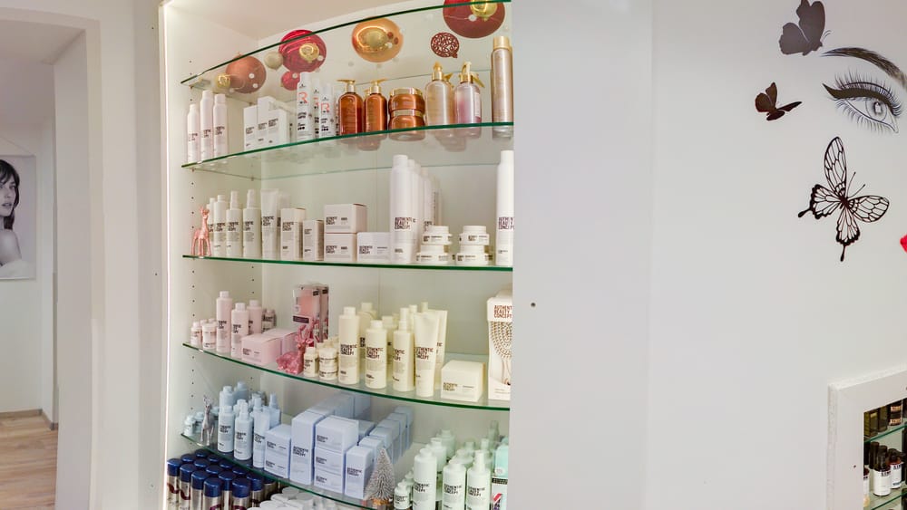 Blick in den Salon: heller Raum mit Empfangstheke, Produktregal und Fußmatte mit dem Logo von Haardesign Viola.